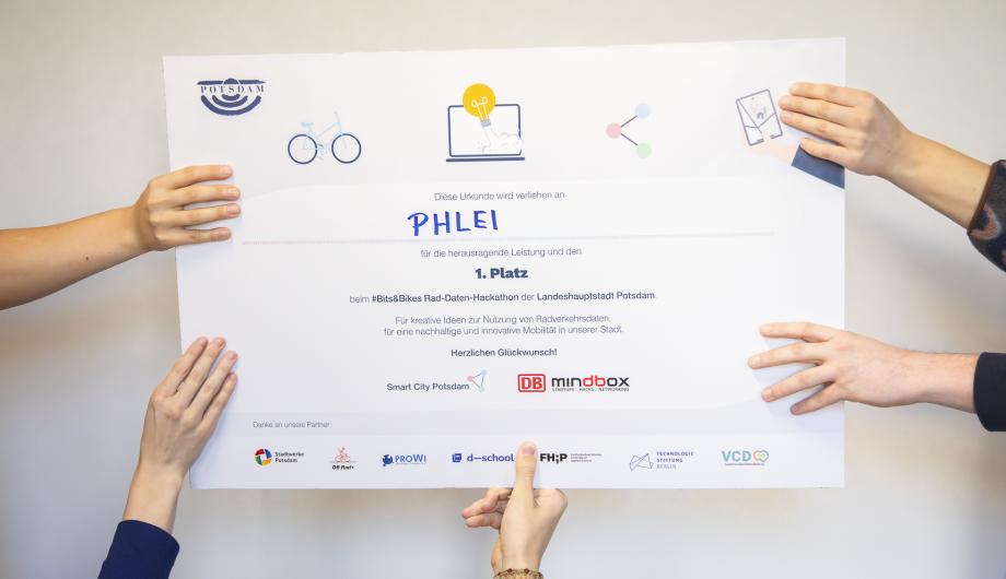 Es sind Hände zu sehen, die eine Urkunde hochhalten